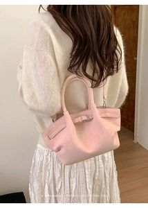 Detalle de bolso tipo cubo plisado rosa claro con hebilla metálica en escena de estilo