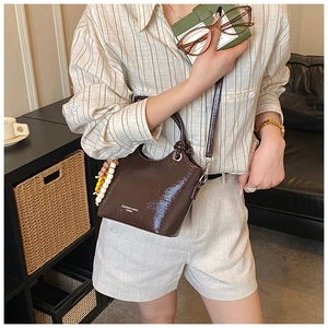 Sac seau en cuir verni marron foncé avec imprimé mode et breloque en perles