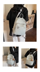Detail of light green PU leather backpack with silver zippers and a brown pompom charm
