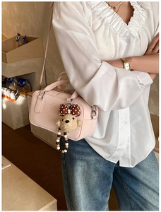 Détail d'un sac Boston rose pâle avec un charm ours porté par un mannequin femme