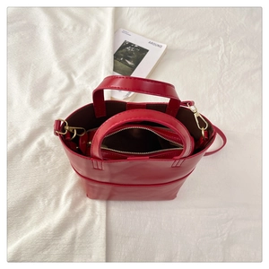 Détail du sac à main en cuir verni rouge avec pochette interne et boucles dorées