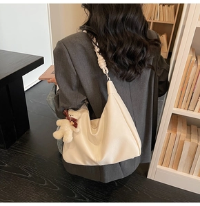 Detail of off-white leather hobo bag with unique knot shoulder strap and bear charm