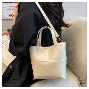 Sac fourre-tout chic en cuir crème porté à l'épaule, style minimaliste pour le quotidien