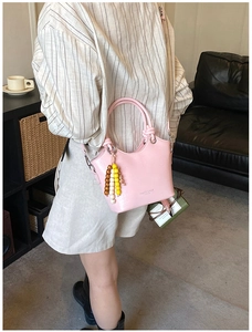 Rosa Beuteltasche aus Leder mit Narbung, bunten Perlenanhänger und geknotetem Griff