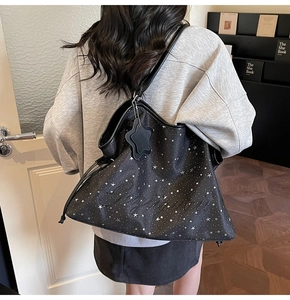 Détail d'un grand sac fourre-tout noir à motif d'étoiles avec breloque et lettrage