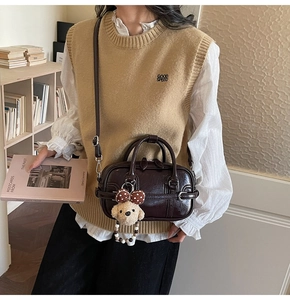 Detail of dark brown mini Boston bag with plush puppy pendant and adjustable shoulder strap