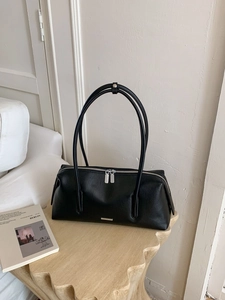 Klassische schwarze Boston-Tasche aus Leder mit silbernen Details auf Holzmöbeln