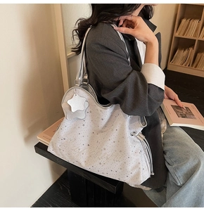 Détail d'un grand sac cabas gris avec imprimé étoiles et broderie dans une bibliothèque