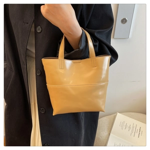Détail d'un sac seau vintage en cuir ciré jaune clair avec poignées et surpiqûres