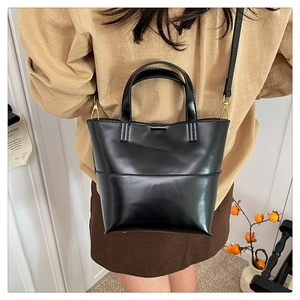 Détail d'un sac seau vintage en cuir ciré noir avec des finitions dorées élégantes