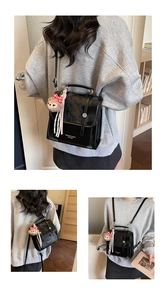 Detail of a vintage black patent leather satchel with metal clasp and plush bear charm