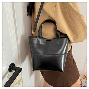 Détail d'un cabas minimaliste en cuir noir brillant avec bandoulière réglable