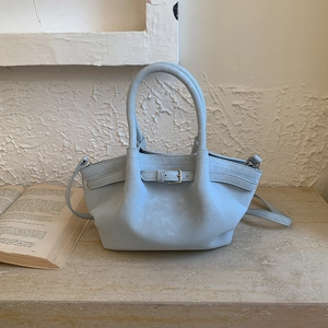 Detalle de bolso tipo cubo azul claro en cuero con hebilla y asas dobles