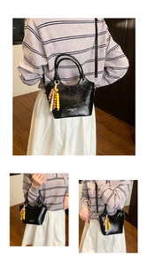 Detail der schwarzen Lackleder-Tasche mit Holzperlen-Anhänger und modischem Branding