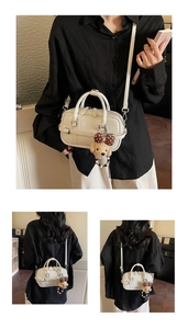 Detail of cream white small crossbody bag with teddy bear charm and strap shown on model