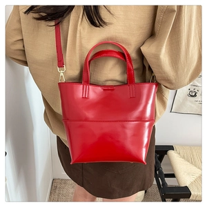 Détail d'un sac cabas en cuir rouge brillant avec boucle de bandoulière dorée