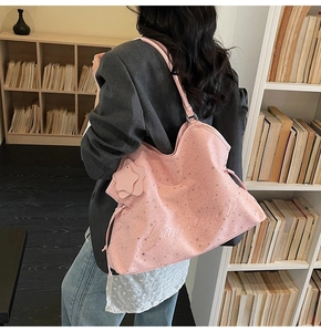 Vue détaillée du sac cabas rose avec motifs d'étoiles sur fond d'étagère blanche avec livres