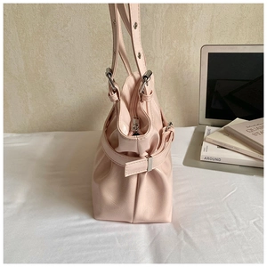 Close-up of light pink tote bag featuring silver buckles and textured leather side detail