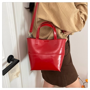 Sac seau rouge brillant en cuir ciré vintage porté avec poignées par un modèle