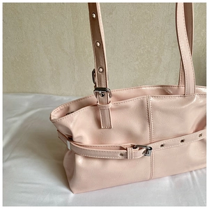 Detail of pink crinkled patent leather shoulder bag with silver buckle and eyelets
