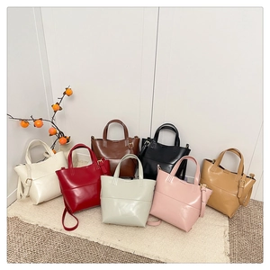 Plusieurs sacs à bandoulière en cuir coloré disposés sur un tapis dans divers tons