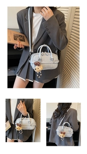 Detail of light blue crossbody bag featuring a plush puppy charm and adjustable strap
