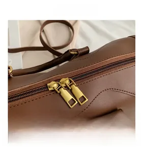 Close-up of caramel leather handbag featuring double matte gold zippers and fine stitching