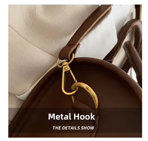 Close-up of golden metal hooks and fine stitching on a dark brown leather handbag detail