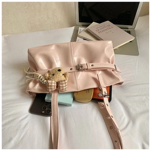 Pink glossy tote bag with teddy bear charm shown with daily essentials on white bedding