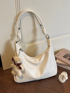 Creamy white oversized dumpling bag with a cute bear charm and a knotted shoulder strap