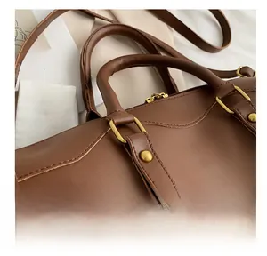 Detail of the reinforced handle attachment with gold-tone hardware on a brown handbag