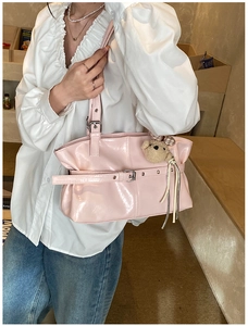 Pink patent leather tote bag detail with decorative belt buckle and cute teddy bear charm