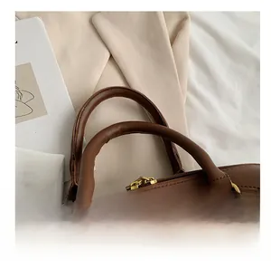 Close-up of brown leather handbag with golden metal buckles and round handles detail