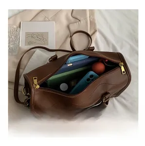 Detail view of brown cylinder handbag interior showing spacious capacity for phone and cosmetics