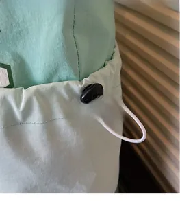Detail view of mint green tote bag showing adjustable drawstring and black plastic cord lock