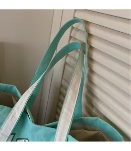 Detail of wide webbed shoulder strap on large canvas tote bag with contrast stitching