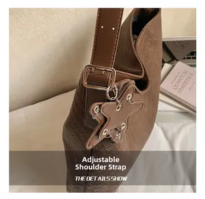 Detail of a brown woven bucket bag featuring an adjustable strap with a gold metal buckle