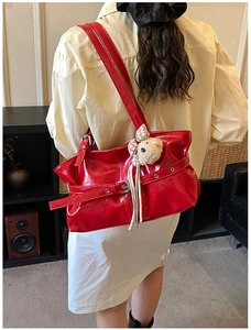 Macro detail of red patent leather tote bag with silver buckle and plush doll charm