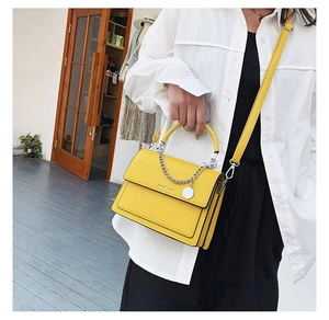 Sac à bandoulière jaune vif à chaîne porté avec une tenue moderne en extérieur