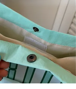 Close-up of the metal magnetic clasp on a mint green nylon tote bag with beige lining
