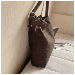Detail of dark brown leather woven tote bag with star pendant in indoor scene