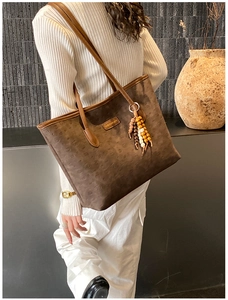 Detail of dark brown tote bag with textured pattern and multi-color beaded charm