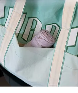 Detail of mint green tote bag featuring a front pocket for umbrella storage