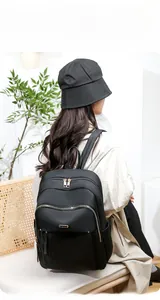 Model wearing black Oxford cloth backpack with gold zippers and stylish side view