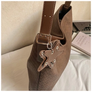 Detail of dark brown woven tote bag featuring an adjustable strap and star-shaped charm