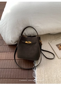 Detail of dark brown leather bucket bag featuring a vintage gold twist-lock closure
