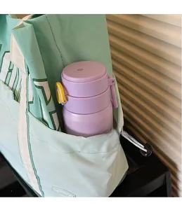 Detail view of the mint green tote bag showing a side pocket holding a purple thermos bottle