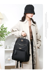 Detail view of the black Oxford cloth backpack with gold zippers and layered storage