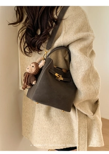 Detail of retro leather handbag with metal lock and a cute brown knitted monkey charm