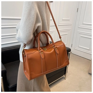 Caramel brown Boston bag styled with a white knit top and skirt in a modern indoor setting